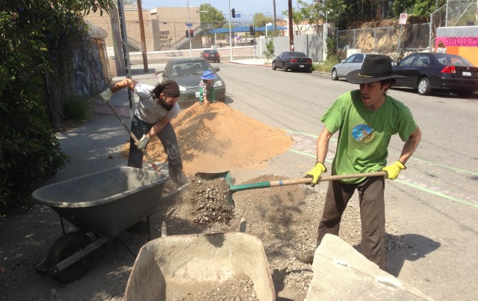 Thiago and Peter shoveling gravel into wheelbarrows to transport it into the LAEV courtyard.